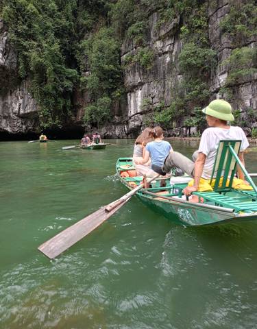 People rowing boats in a clear green river with cliffs