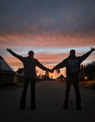 Two people holding hands against a vibrant sunset.