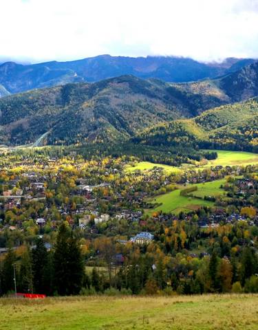 Panoramic view of a town surrounded by mountains in autumn.