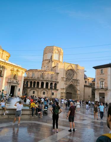 A bustling plaza with historic buildings and a fountain.