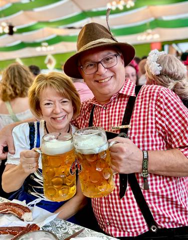A couple toasting with large beer mugs at Oktoberfest.