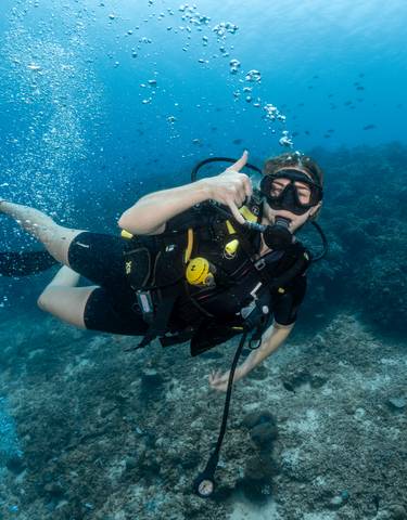 Underwater scuba diver raising a thumb up.