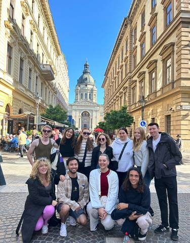 Group photo in a city with a grand building in the background.