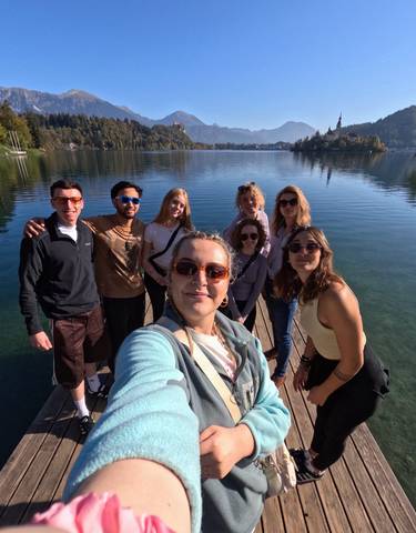 Group of people by a lake on a sunny day in a scenic landscape.