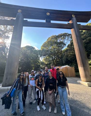 Group of people posing outdoors with large wooden gates and trees.