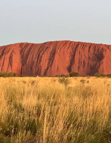 Uluru, a large sandstone rock formation illuminated by sunlight