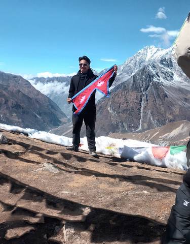 Person holding a flag in a snowy mountainous landscape.