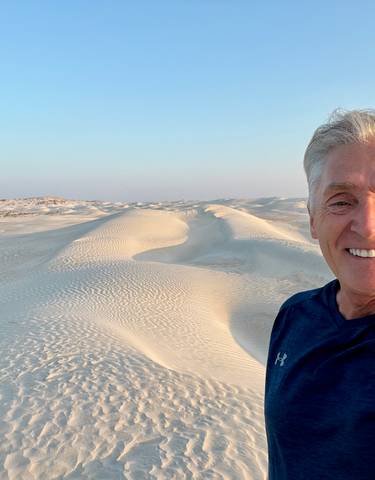 Man smiling with sand dunes in the background.