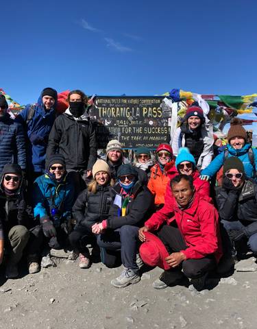 Group of people at Thorong La Pass with prayer flags.