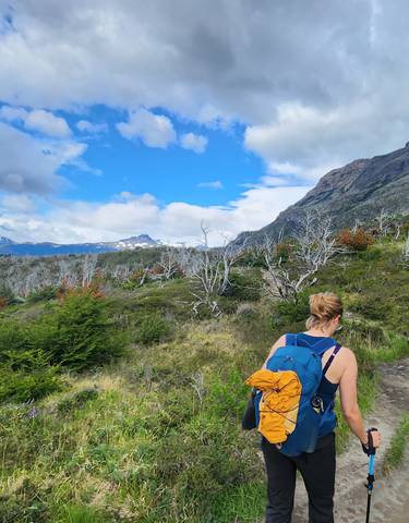 Hiker walking along a scenic trail surrounded by mountains.