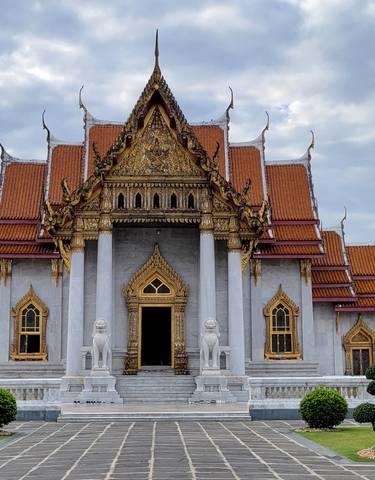 Ornate temple with golden roof and cloudy sky.