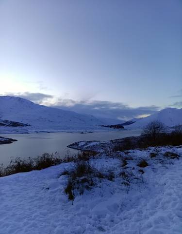 Snow-covered landscape with a body of water and mountains.