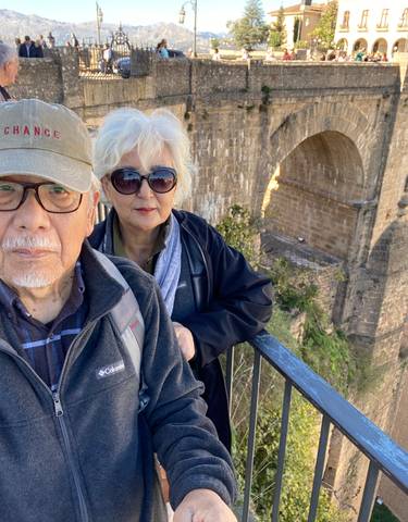 Elderly couple in front of a large stone bridge.