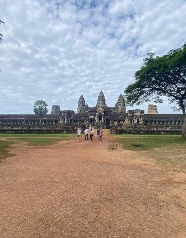 Wide-angle view of Angkor Wat temple with people walking towards it.