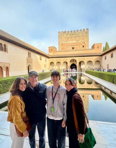 Family posing in front of a water reflection at a historic site.