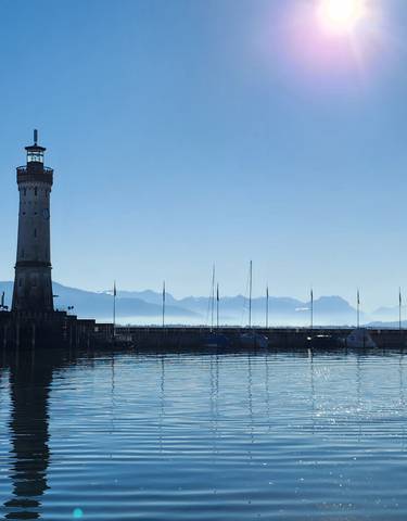 Harbor scene with lighthouse and distant mountains.
