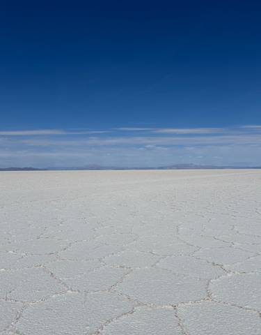 Expansive view of the Uyuni Salt Flats under a clear blue sky.