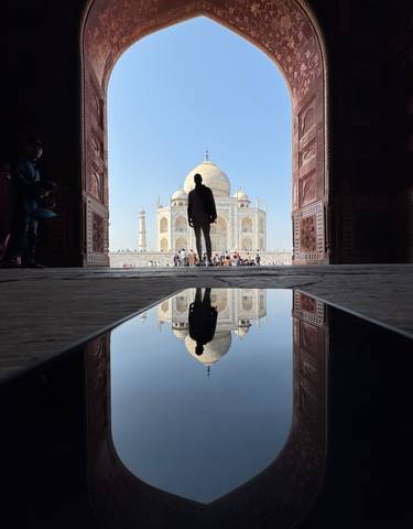 Reflection of Taj Mahal in a pool with a silhouette.
