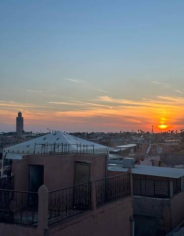 Sunset over a cityscape with distant skyline and mosque tower.