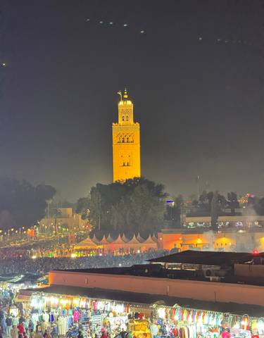 Illuminated minaret tower at night in a cityscape.