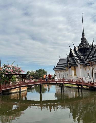 A traditional Thai architectural structure with a bridge over a pond.