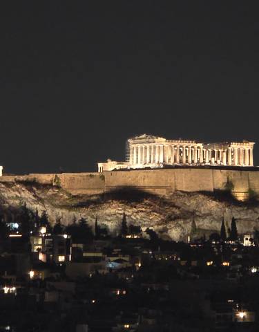 Night view of a lit Acropolis against a dark sky.