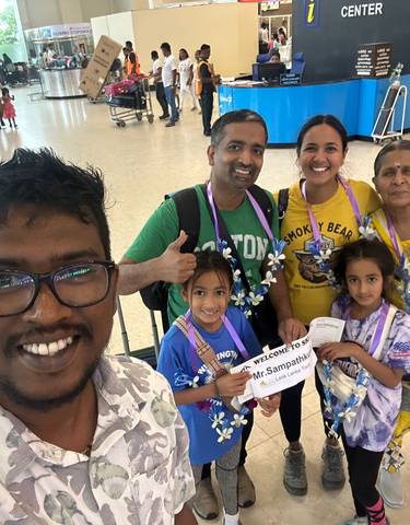 A smiling family group being welcomed at an airport.