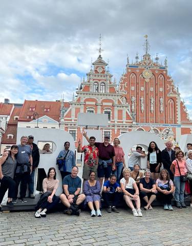 Large group of people posing in front of a historic building.