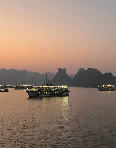 Numerous boats sailing on a serene bay at sunset.