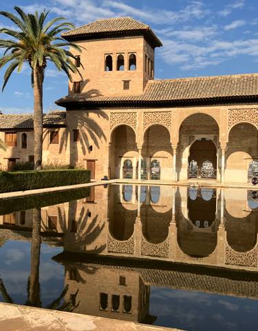 Reflective pool with a historic building featuring arches.