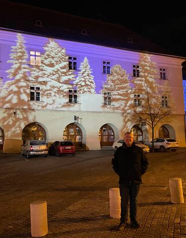 Illuminated building at night with people and cars.