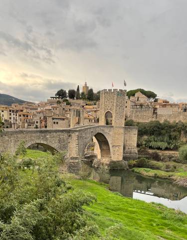 Historic stone bridge over a river leading to a village.