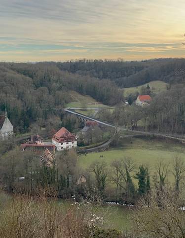 Expansive view of fields and houses with a bridge at sunset.