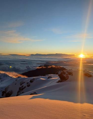 Dramatic sunrise view from a snowy mountain peak.