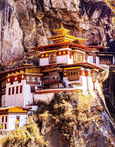 Tiger's Nest Monastery built into a cliff, surrounded by nature, under a clear blue sky.