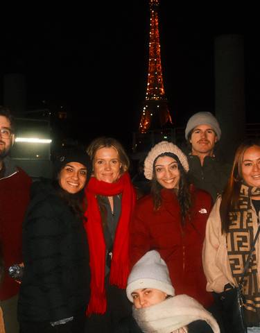 Group of people in winter clothing posing at night with a landmark.