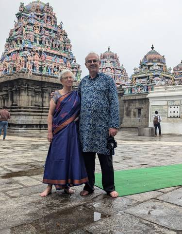 Older couple in traditional attire in front of a temple.
