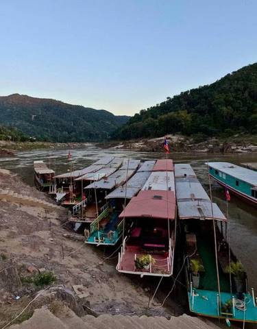 Boats lined up along a riverbank at sunset.