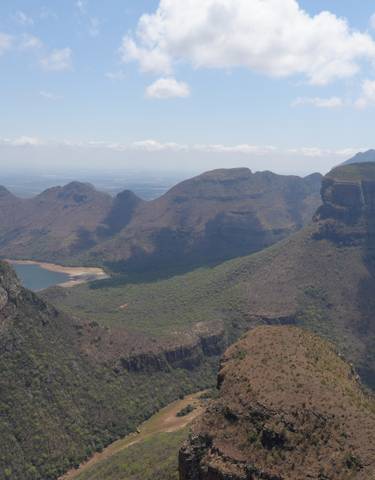 Panoramic view of a mountain range with valleys and a lake.