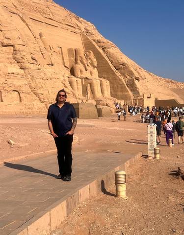 Person in front of the statues of Abu Simbel with tourists in the background.