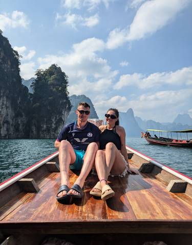 Couple on a boat with mountainous backdrop.