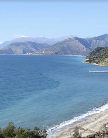 Coastal area with a curve of sandy beach and hills.