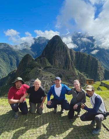 Group of people posing in front of Machu Picchu.