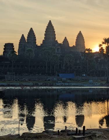 Sunrise view of Angkor Wat with its reflection in a pond.