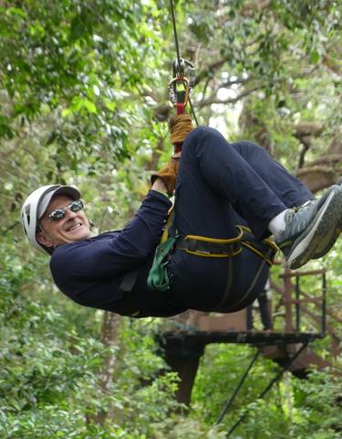A person zip-lining through a forest.