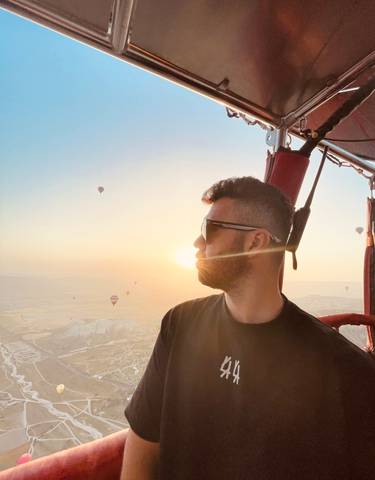 Person enjoying a hot air balloon ride at sunrise.