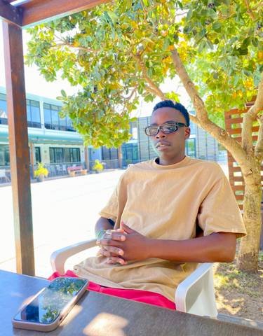 Person sitting under a tree in a sunny outdoor setting.