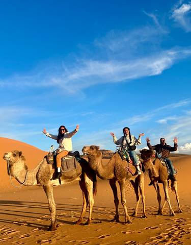 People riding camels in the desert.
