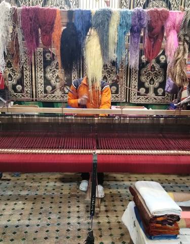 A person working on a traditional weaving loom with colorful textiles.