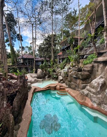 Natural rock formations with small pools and rustic buildings.
